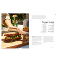 Person cutting a sandwich on a wooden board with a blurred background