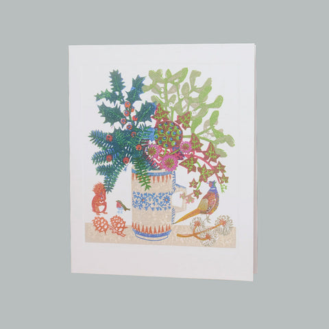 A white greeting card featuring a colorful illustration of a floral arrangement in a patterned vase, with a pheasant, squirrel, and small birds, shown against a solid gray background.