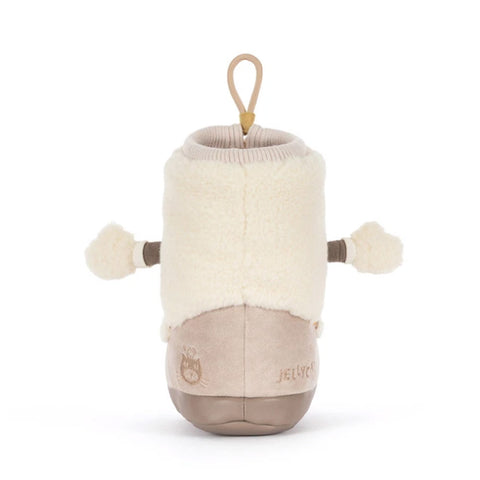 A plush baby bootie toy by Jellycotton, featuring a cream faux fur upper, a beige suede-like lower section with embroidered brand text, and small brown pom-pom arms on a white background.