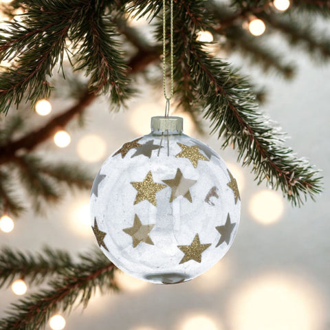 Decorative Christmas ball ornament with gold stars hanging on a tree branch.