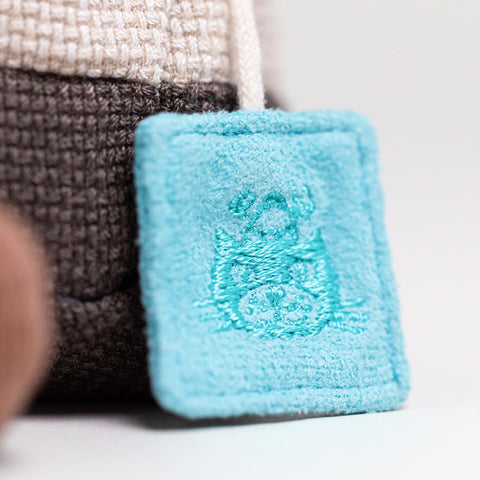 Turquoise fabric tag with a logo on a neutral background