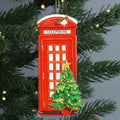 Red telephone box Christmas ornament with a small tree on a green branch background