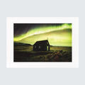 A square art print featuring a dark church silhouette under a dramatic green aurora borealis sky, presented with a wide white border on a light gray background.