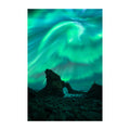 A vertical photographic print of the northern lights over a rocky coastal landscape, with glowing green and teal aurora sweeping across the night sky above dark rock formations.