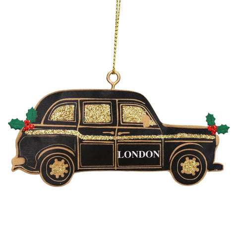 A London cab Christmas ornament shaped like a black taxi with gold glitter details, green holly leaves, red berries, and the word 'LONDON' on the side, hanging from a gold string.