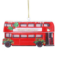 A red double-decker bus Christmas ornament with 'Merry Christmas' written across the front, decorated with green holly leaves and red berries, hanging from a gold string.