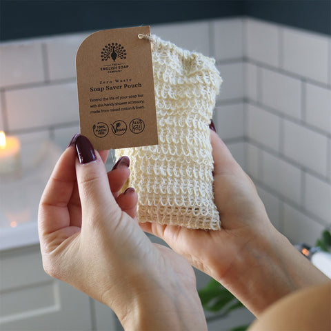 Person holding a natural soap saver pouch with a label in a bathroom setting