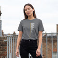 Woman wearing a gray t-shirt with text on it, standing on a rooftop with brick walls and railings.