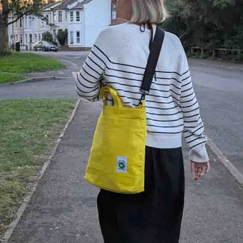 A women carrying a yellow Cora + Spink Otter tote bag 
