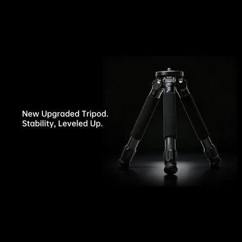 A black tripod photographed on a black studio background with white text on the left reading 'New Upgraded Tripod. Stability, Leveled Up.