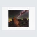 A photographic art print featuring a night desert landscape with large rock formations under a star-filled sky and the Milky Way