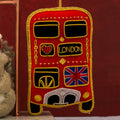 Decorative red london bus front ornament with gold accents on a red background