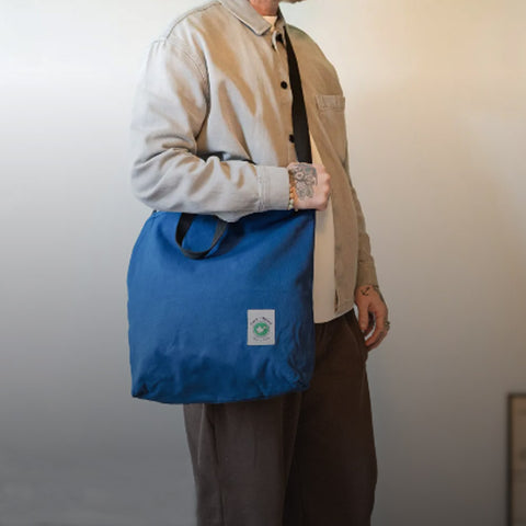 man carrying a blue cora + spink otter sack tote bag