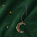 Moon-shaped brass decoration on a green fabric background with gold stars