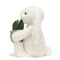 Cream plush bunny toy holding a plant in pot, side view