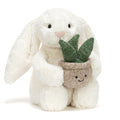 Cream plush bunny toy holding a plant in a beige pot