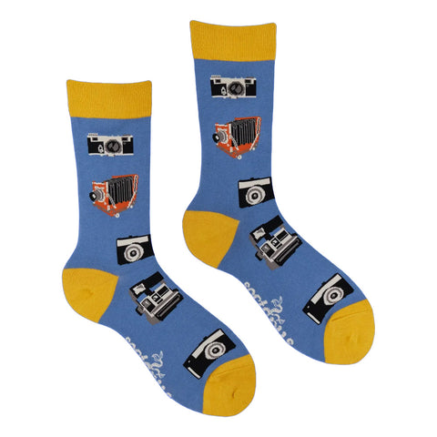 A pair of crew socks with a blue body, yellow toe and cuff, and a pattern of vintage cameras