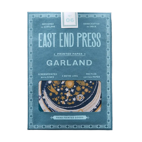 East End Press Garland printed paper in a dusty blue box, featuring a window that shows a patterned navy and gold garland, with text highlighting its handcrafted and recycled qualities.