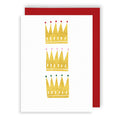 Three gold glittery crowns on a white card with a red envelope.