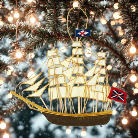 Decorative Cutty Sark ship ornament on a Christmas tree with lights in the background