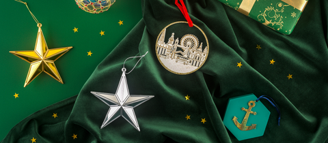 Gold star, silver star, gold bauble, London skyline hanging decoration and Cutty Sark anchor decorations against a green background