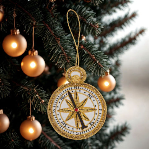 Decorative compass ornament on a Christmas tree with gold bulbs.