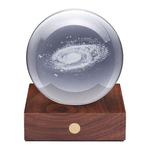 3D laser-engraved galaxy in a crystal ball on a wooden stand.