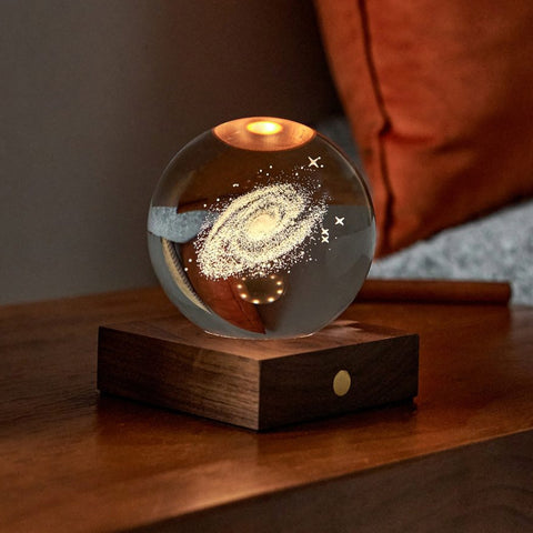 Lit 3D laser-engraved galaxy in a crystal ball on a wooden stand.