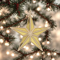 Decorative gold star ornament hanging on a Christmas tree with lights in the background