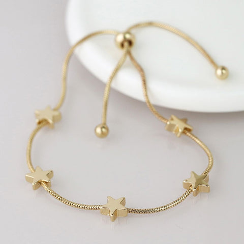 Gold bracelet with star-shaped charms on a light gray background