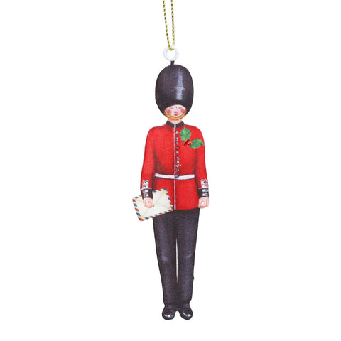 A hanging ornament shaped like a British Royal Marines guard in a red uniform with a black bear hat, holding a small envelope.