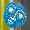 Blue and silver decorative circular piece with moon face design 