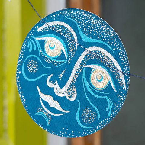 Blue and silver decorative circular piece with moon face design 