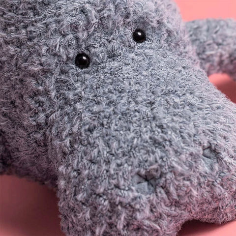 Close-up of a grey manatee plush toy with black eyes 