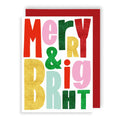 A festive greeting card with the words 'Merry & Big' in large, colorful glitter-textured letters on a white background, shown with a red envelope behind it.