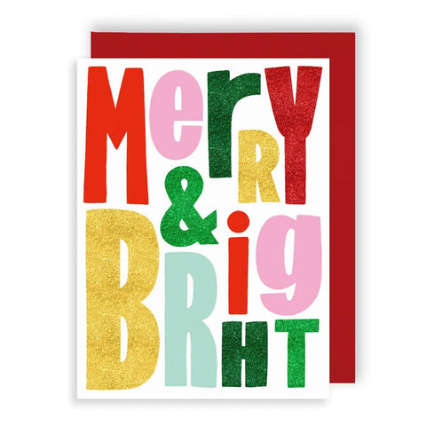 A festive greeting card with the words 'Merry & Big' in large, colorful glitter-textured letters on a white background, shown with a red envelope behind it.