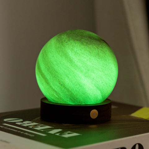 Green glowing sphere on a black base with a blurred background