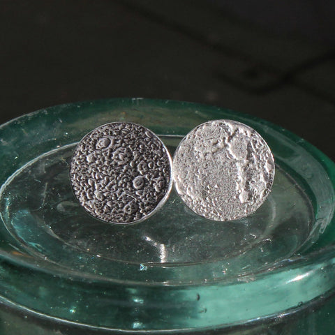 Round, textured silver earrings resembling the dark and light Moon.