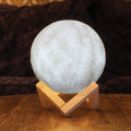 Moon-shaped lamp on a wooden stand with a dark brown background
