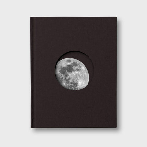 Black book with a circular cutout displaying the moon 