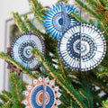 Decorative circular ornaments with spiral patterns hanging on a Christmas tree.