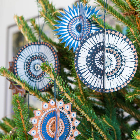 Decorative circular ornaments with spiral patterns hanging on a Christmas tree.