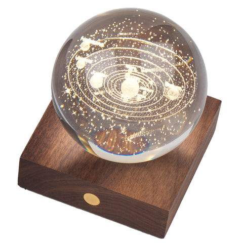 3D laser-engraved design of the solar system in a crystal ball on a wooden base.