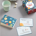 Space-themed trivia cards and packaging on a table with a cup and popcorn.