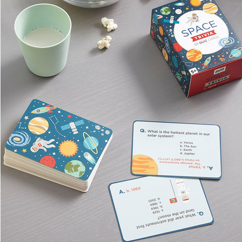 Space-themed trivia cards and packaging on a table with a cup and popcorn.