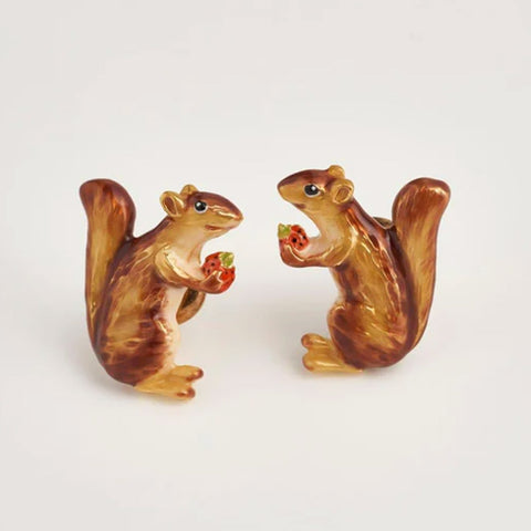 Two non-identical brown enamel squirrel-shaped earrings, each is holding a strawberry.