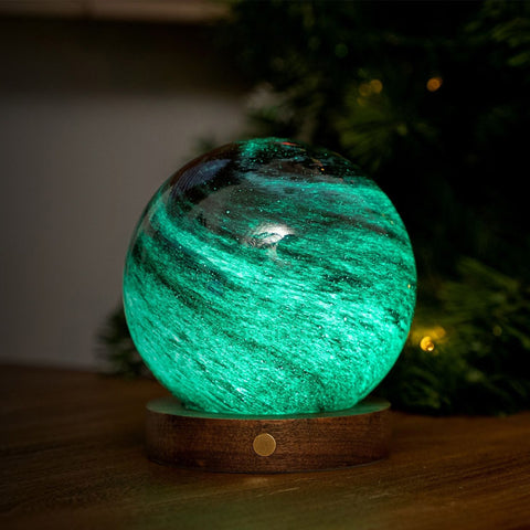 Glowing green spherical light on a wooden base with a blurred background