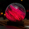 Glowing red and black sphere on a wooden stand with blurred lights in the background