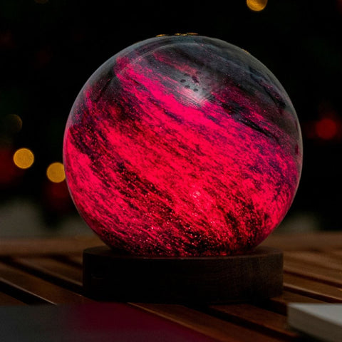 Glowing red and black sphere on a wooden stand with blurred lights in the background