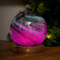 Glowing pink and purple sphere on a wooden base 